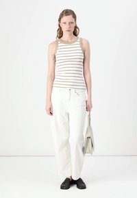 Ribaga tank top kreemja ja beeži triibuga, koos lõdva valge džinniga ja mustade mokassiinidega. Lisandub minimalistlik beež käekott.