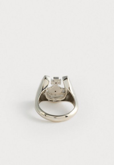 Ezüst tónusú gyűrű sima, kerek formával és üreges középrésszel. Egyszerű keresztmotívum a tetején; fényes felület, amely visszatükrözi a fényt.