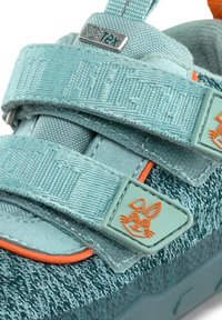 Scarpa per bambini di colore blu acquamarina con tessuto testurizzato, due cinturini con chiusura a velcro e una decorativa faccia di coniglio arancione sul lato.