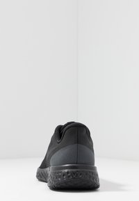 Zapatilla deportiva negra con un upper texturizado, silueta aerodinámica y una suela negra acolchada con un brillo sutil.