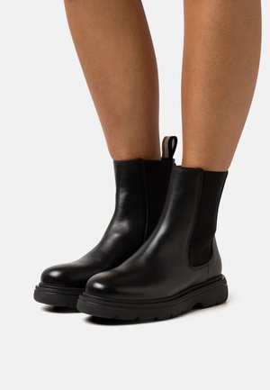 Stivaletti alla caviglia in pelle nera con pannelli elastici laterali, suola testurizzata e anello sul retro per facilitare la calzata.