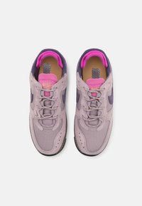 Zapatillas Nike en violeta y rosa con un upper texturizado de ante y malla, puntera redondeada y un área de cordones con patrón. Suela de goma con acentos en puntos.