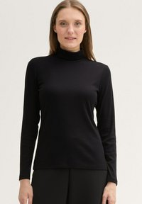 Schwarzes Langarm-Turtleneck-Shirt mit geribbelter Textur und schlanker Passform, gefertigt aus einem weichen Material, das sich gut für Lagen eignet.