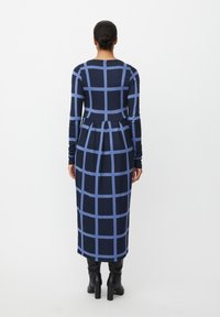 Sukienka z długim rękawem w granatowo-jasnoniebieską kratę, z dopasowanym górnym bielizną i rozkloszowanym dołem, wykonana z miękkiego, elastycznego materiału.