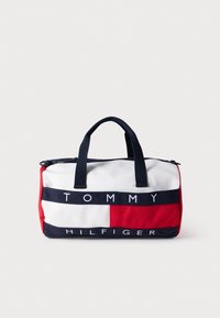 Κόκκινη, λευκή και μπλε τσάντα από καμβά με στρογγυλό σχήμα, διπλές λαβές και κλείσιμο με φερμουάρ. Φέρει την επιγραφή «TOMMY HILFIGER» με έντονα γράμματα στο μπροστινό μέρος.