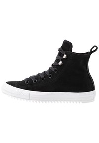 Schwarze Wildleder-Hochtop-Sneaker mit grauen Schnürsenkeln, silbernen Ösen und einer weißen Gummisohle mit strukturiertem Rand und einem Zugtab.