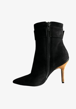 Stivale alla caviglia in suede nero con punta affusolata, cerniera laterale e tacco a stiletto in sughero. Presenta un design a risvolto nella parte superiore.
