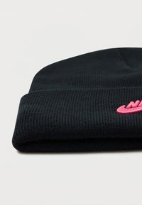 Fekete kötött sapka bordázott textúrával, elöl rózsaszín hímzett logóval, a karimánál felhajtva.