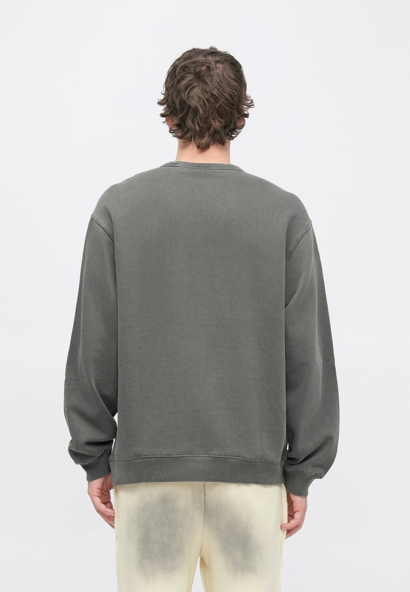 Grå sweatshirt med avslappnad passform, ribbade muddar och rund halsringning. Material av bomullsblandning, enfärgad baksida, använd med ljusa byxor.