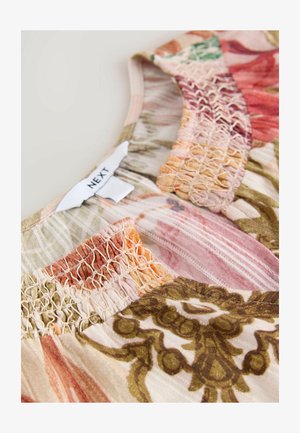 Bluzka bez rękawów w kwiatowy wzór, wykonana z miękkiego materiału, z elastycznym marszczeniem typu smock oraz metką z napisem "NEXT" przy dekolcie.