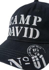 Black baseball cap featuring "CAMP DAVID" in white embroidered text, with additional white graphic patterns and stitching details on the brim.