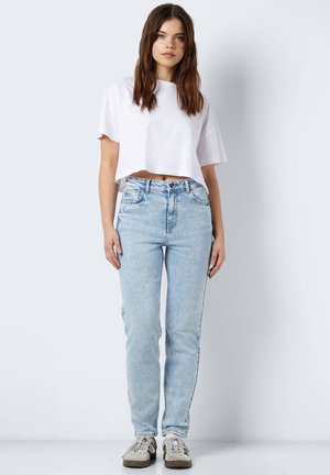 T-shirt blanc court, jeans taille haute bleu clair, et baskets grises. Les jeans présentent une coupe droite classique et une légère décoloration.