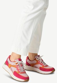 Adidași sportivi cu un amestec de piele întoarsă roz și portocalie și materiale din plasă, având o talpă groasă albă și șireturi albe în contrast.