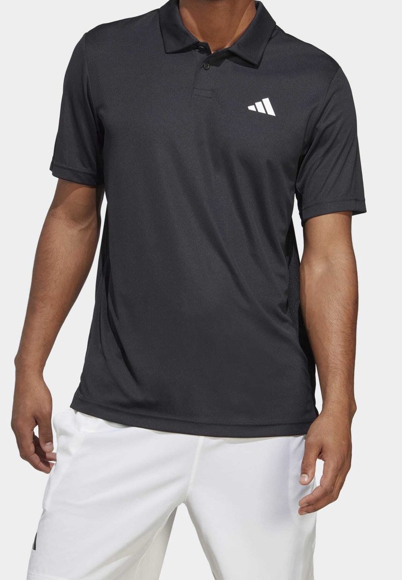 Černé polo tričko z prodyšné látky, s bílým logem ve tvaru tří pruhů na levé straně hrudi, klasickým límečkem a krátkými rukávy.