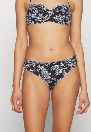 Juodas bikinis su baltais gėlių raštais. Viršus turi paminkštintą, struktūrizuotą dizainą; apatiniai turi žemą juosmenį ir sušukuotas šonines detales.