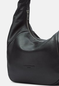 Borsa a spalla in pelle nera con un design morbido, chiusura con zip argentata, logo impresso e texture liscia. Presenta una forma arrotondata.