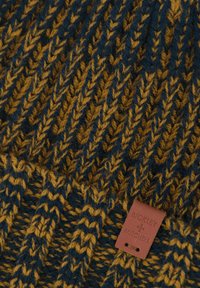 Dzianinowa czapka w kolorze granatowym i musztardowym z fakturowanym wzorem zygzaków. Zawiera brązową skórzaną metkę z wytłoczonym napisem „BICKLEY + MITCHELL”.