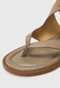 Brown flip-flop sandal with a suede strap, featuring a soft, padded footbed and contrast stitching along the edge of the outsole.