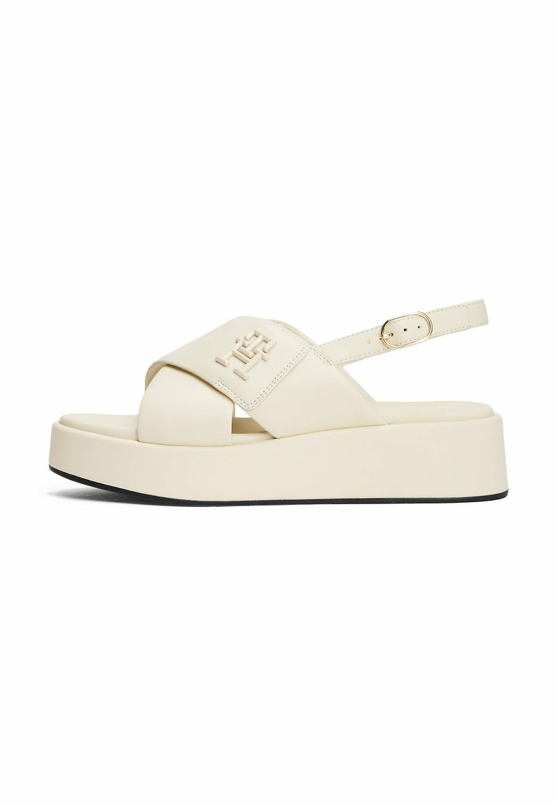 Crème-kleurige platformsandalen met een brede kruissluiting, verstelbare enkelband en zwarte rubberen zool. Voorzien van een reliëf merkdetail.