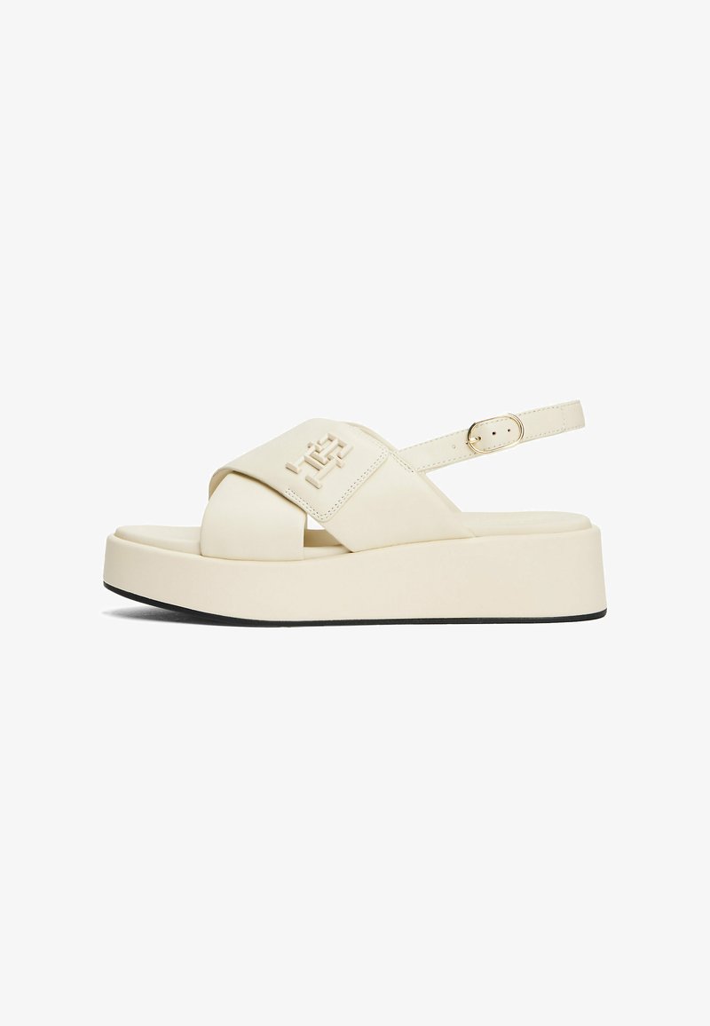 Crème-kleurige platformsandalen met een brede kruissluiting, verstelbare enkelband en zwarte rubberen zool. Voorzien van een reliëf merkdetail.