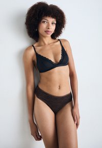 Black lace-trimmed bralette with adjustable straps paired with brown striped high-waisted panties, showcasing soft textures and contrasting patterns.