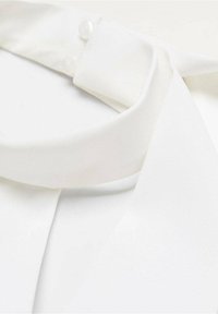 Col blanc de chemisier avec un tissu lisse, deux boutons fixés et un design fluide. Texture douce avec une silhouette classique.