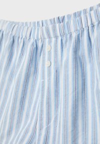 Tissu à rayures verticales bleu clair et blanc avec deux boutons blancs et un détail de taille élastique.