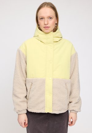 Yellow and beige jacket with a hood, featuring a soft, fluffy texture and two zippered side pockets. Snap buttons along the front.
