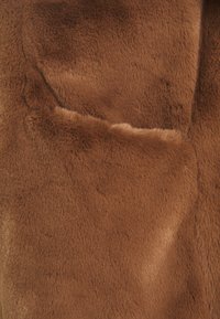 Brown faux fur fabric with a soft, dense texture and a smooth finish. The surface features subtle variations in shade and sheen.