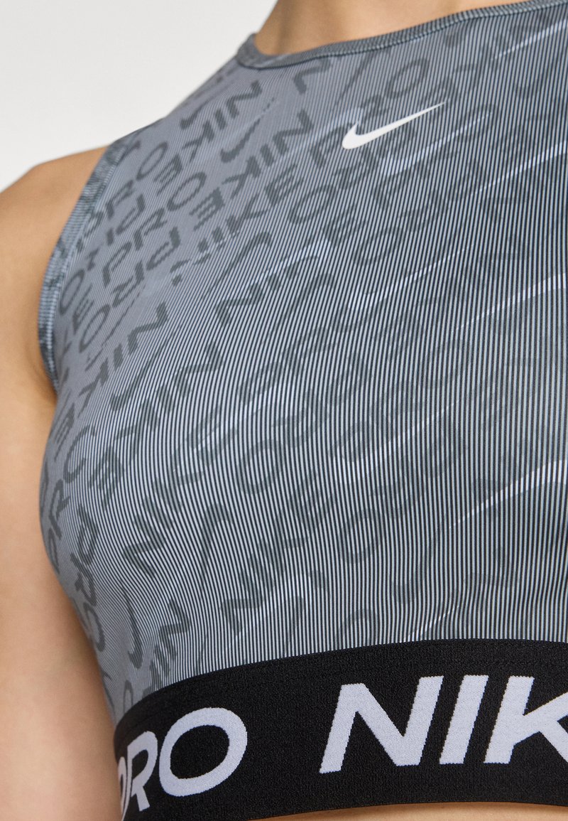 Grauer Sport-BH mit horizontalen Streifen, ausgestattet mit einem schwarzen Elastikband mit "NIKE" in Weiß und einem kleinen weißen Nike-Logo auf der Brust.