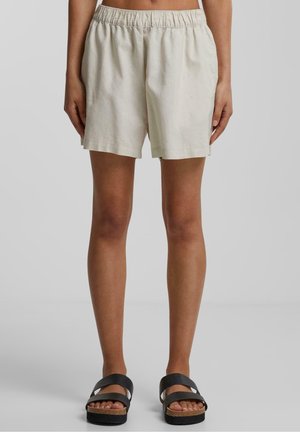 Lichtbeige linnen shorts met een elastische tailleband, met een losse pasvorm en een recht broekspijp ontwerp. Gecombineerd met zwarte sandalen met bandjes.