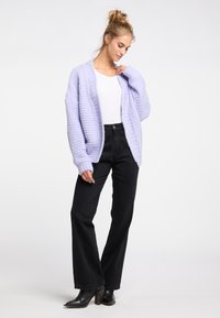 Chunky stickad cardigan i ljus lavendel, öppen front, långa ärmar. Matchad med hög midja svarta utsvängda jeans och svarta klackstövlar.