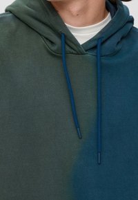 Mikina s kapucí v odstínech zelené a modré s kapsou kangaroo, stahovacími šňůrkami a jemnou texturou látky.