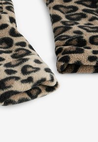 Mäkká fleecová tkanina s leopardím vzorom, preložená, s béžovým podkladom a čiernymi škvrnami po celom povrchu.