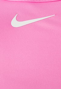 Αθλητική μπλούζα Nike σε φωτεινό ροζ ύφασμα, με λογότυπο Swoosh σε λευκό χρώμα. Το υλικό έχει ριγωτή υφή και εφαρμοστή σχεδίαση.