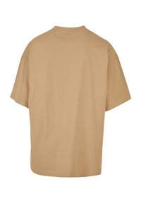 Hamp oversized t-shirt i lys beige med rund halsudskæring og korte ærmer. Glat tekstur uden tryk eller hardwaredetaljer.
