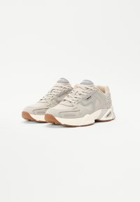 Beige sneakers met een gestructureerd mesh en faux leer accenten, voorzien van een grijs logo, een gevoerde zool en een rubberen gumrubber buitenzool.