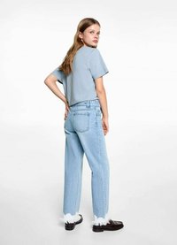 Ljusblå t-shirt med korta ärmar, parat med högmidjade ljusjeans med fransade fållar, bärs med svarta skor.