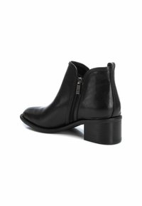 Botas de tobillo de cuero negro con una textura suave, que cuentan con un cierre lateral con cremallera y un diseño de tacón bajo en bloque. Punta redonda y silueta elegante.