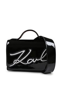 Sac à main en cuir verni noir avec un logo "Karl" blanc bien en évidence, forme structurée, anses supérieures et bandoulière amovible.