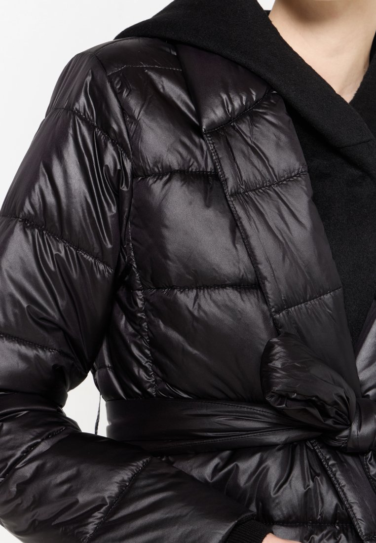 Czarna puchowa kurtka o błyszczącej, pikowanej fakturze, z kapturem i przewiązanym w pasie. Materiał wydaje się miękki i gładki, zapewniając ciepło.