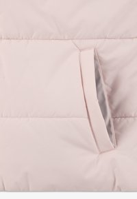 Puhasto jakna v svetlo rožnati tkanini z gladko teksturo. Ima stranski žep z kontrastno notranjo oblogo in vodoravni šivni detajl.