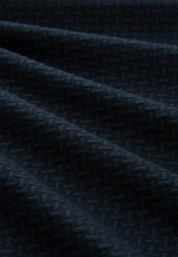 Dunkelnavy-Stoff mit einem strukturierten Gewebe-Muster, das subtile erhobene geometrische Formen zeigt. Weiche, leicht glänzende Textur mit einem glatten Fall.
