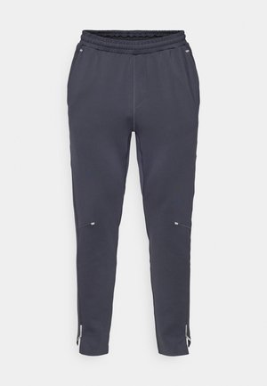 Marineblaue Jogginghosen mit elastischem Bund, Seitentaschen und Reißverschlussabschlüssen. Hergestellt aus weichem Material mit glatter Textur und minimalistischem Design.