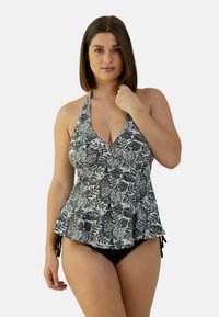Haut de maillot de bain imprimé floral noir et blanc avec un design à col halter, une coupe évasée et des liens sur les côtés, associé à un bas de bikini noir uni.
