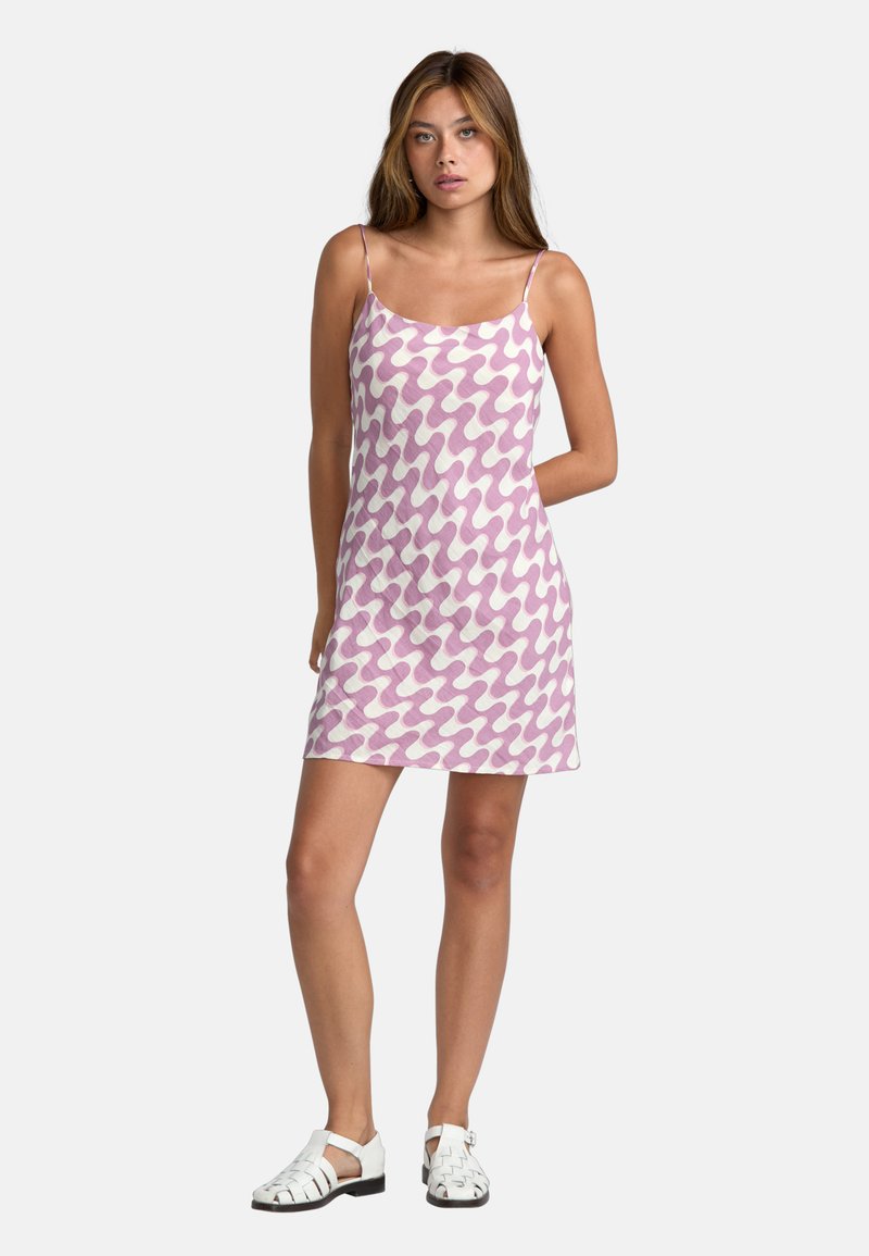 Ärmlös klänning i rosa och vit vågmönster, med avslappnad passform och mjuk textur; modellen bär vita sandaler med remmar.