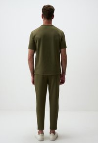 Set a due pezzi verde oliva composto da una maglietta a maniche corte e pantaloni a sigaretta, realizzato in tessuto morbido con una vestibilità comoda e dettagli minimi.