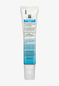 Garnier SOS Anti-Spots Stick in a 10ml flexible tube; clear casing, blue accents, white cap, multi-language text, designed for targeted application.