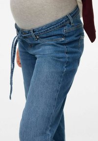 Light blue denim jeans with a mid-rise waist, featuring a tie detail and minimal distressing, paired with a gray shirt visible at the waist.