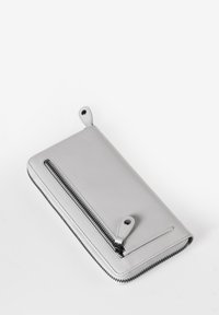 Portafoglio in pelle argentata con chiusura a zip, caratterizzato da un design rettangolare elegante e due dettagli a soffietto negli angoli superiori.